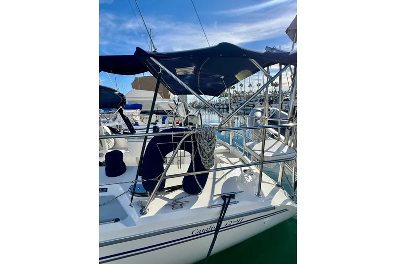 Slide: The Image of 2005 Catalina 42 MkII sailboat docked, featuring blue canopy and polished railings. - 12