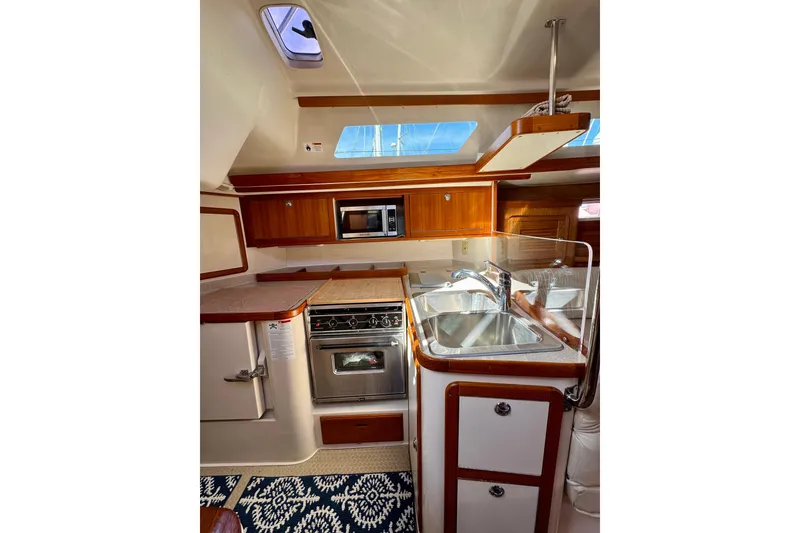 Slide: The Image of 2005 Catalina 42 MkII yacht kitchen with wood cabinetry, stainless steel sink, and modern appliances. - 43