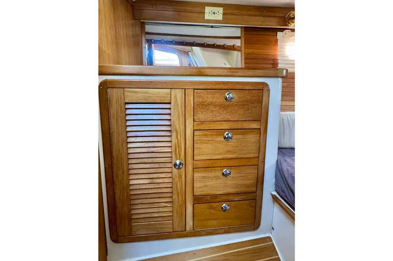 Slide: The Image of Wooden cabinetry inside 2005 Catalina 42 MkII sailboat, featuring drawers and a louvered door. - 62