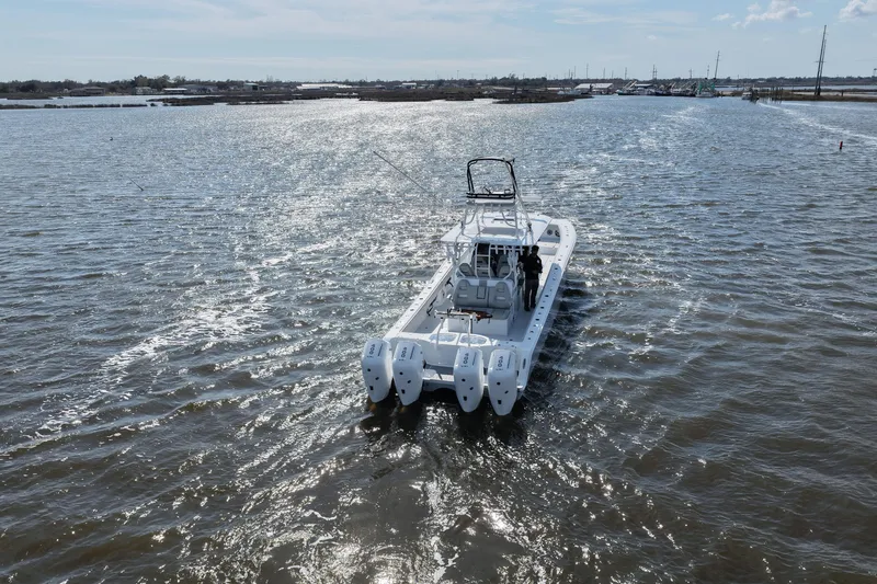 Slide: The Image of Freeman 42LR 2025 boat cruising on a sunny waterway with four engines. - 16