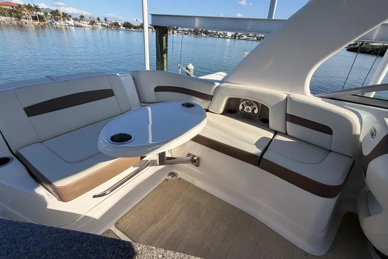 Slide: The Image of 2015 Chaparrall 264 Sunesta boat interior with seating and table, overlooking calm waters. - 18