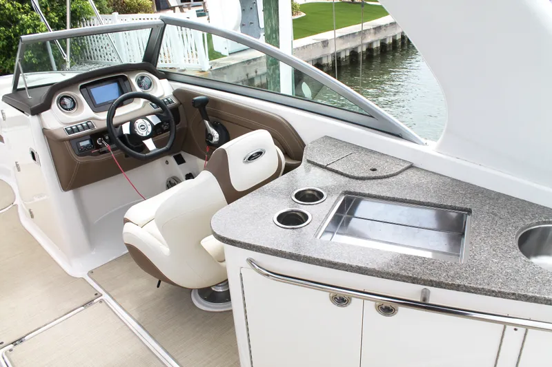 Slide: The Image of 2015 Chaparral Sunesta 264 boat interior with helm, steering wheel, and kitchenette. - 34