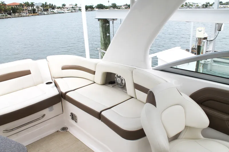 Slide: The Image of 2015 Chaparral Sunesta 264 boat interior with white and brown seating, docked by the water. - 38