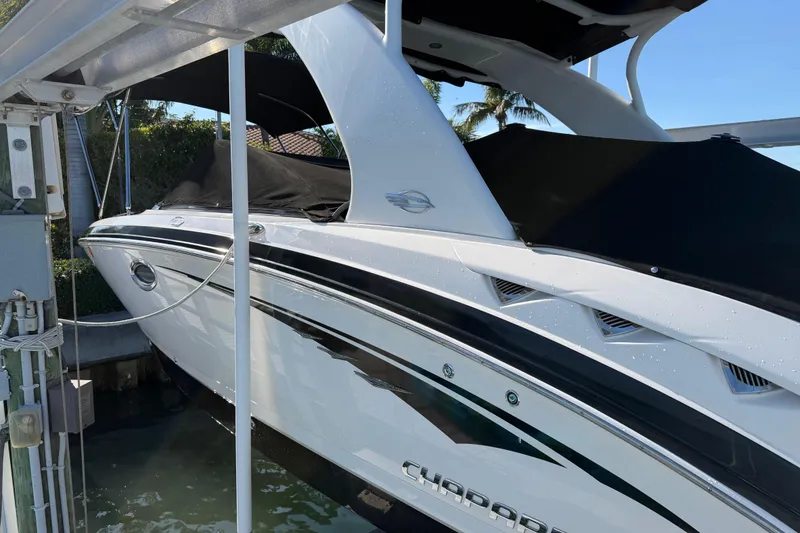Slide: The Image of 2015 Chaparral 264 Sunesta boat docked, featuring sleek design and black canopy. - 6