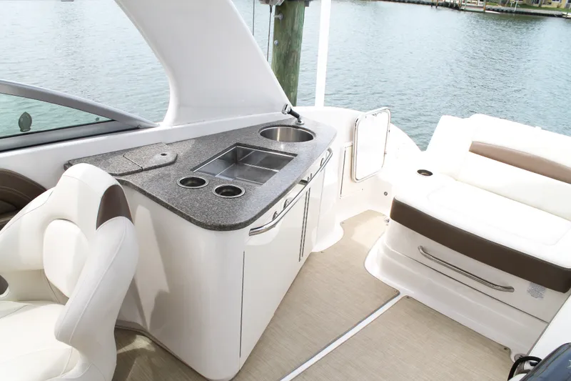 Slide: The Image of 2015 Chaparral Sunesta 264 boat interior with seating and kitchenette by the water. - 39