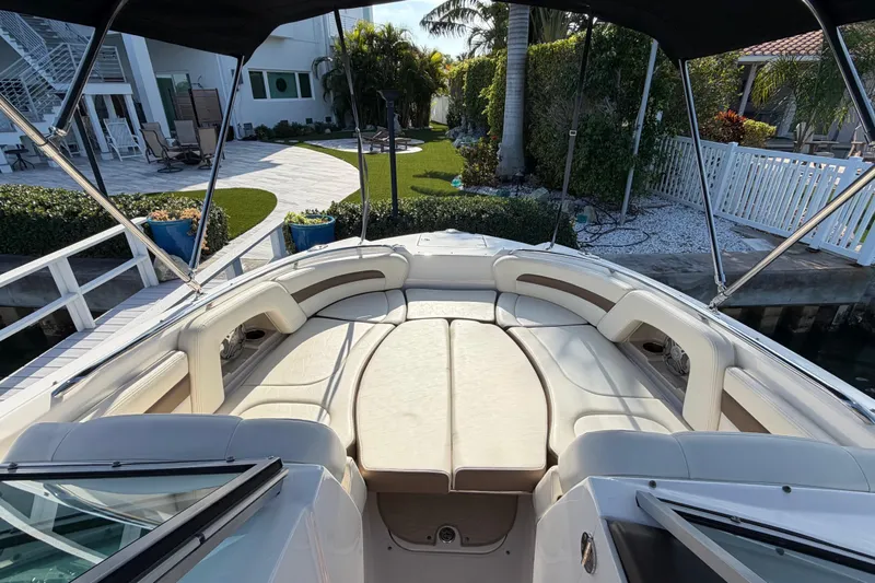 Slide: The Image of 2015 Chaparral 264 Sunesta boat with spacious seating, docked near a landscaped garden. - 8