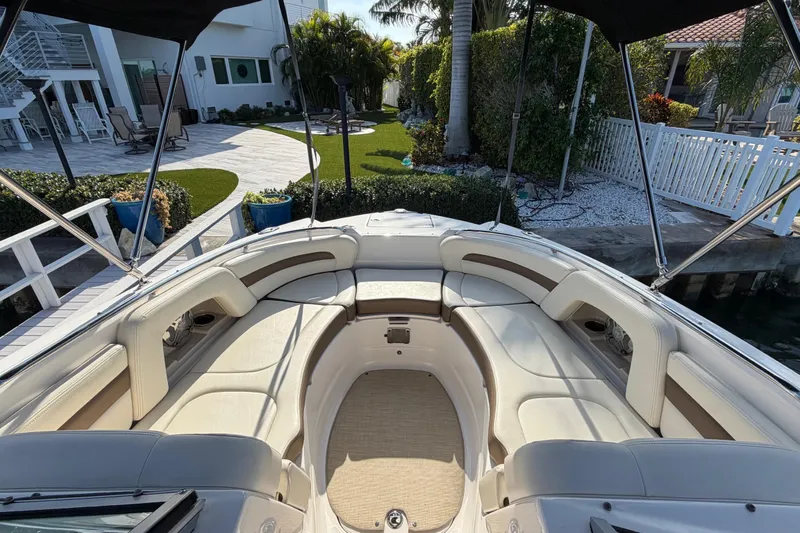 Slide: The Image of 2015 Chaparrall 264 Sunesta boat with spacious seating, docked near a landscaped garden. - 9