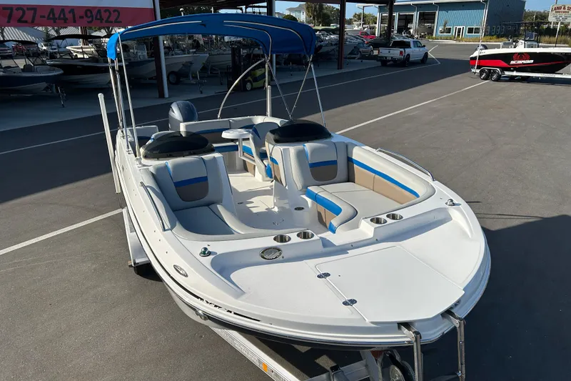 Slide: The Image of 2018 Hurricane Sundeck Sport 218 OB boat with blue canopy in a marina setting. - 6