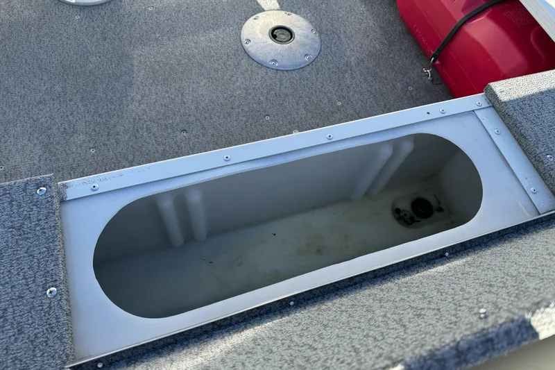 Slide: The Image of 2010 Alumacraft Fisherman 145 CS boat storage compartment with gray carpeted deck. - 12