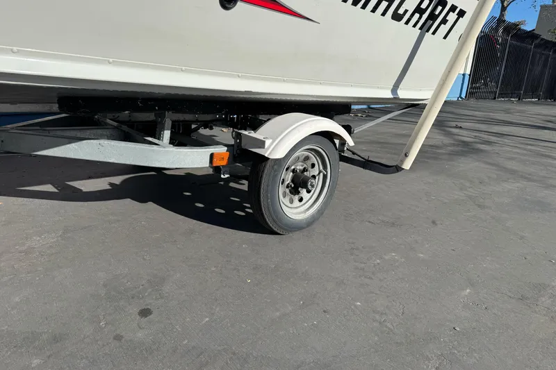 Slide: The Image of 2010 Alumacraft Fisherman 145 CS boat trailer on pavement, close-up view. - 2