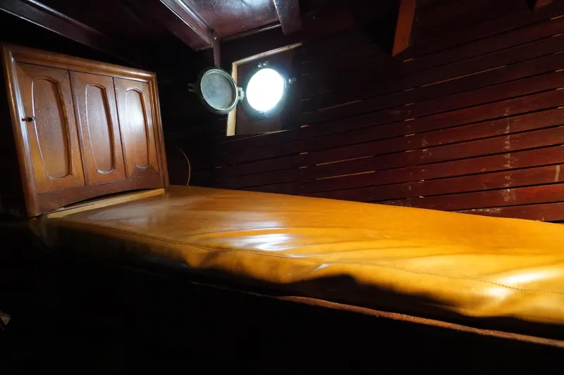 Slide: The Image of Cozy wooden cabin interior of a 1976 Manila Shipbuilders sailboat with a porthole window. - 14