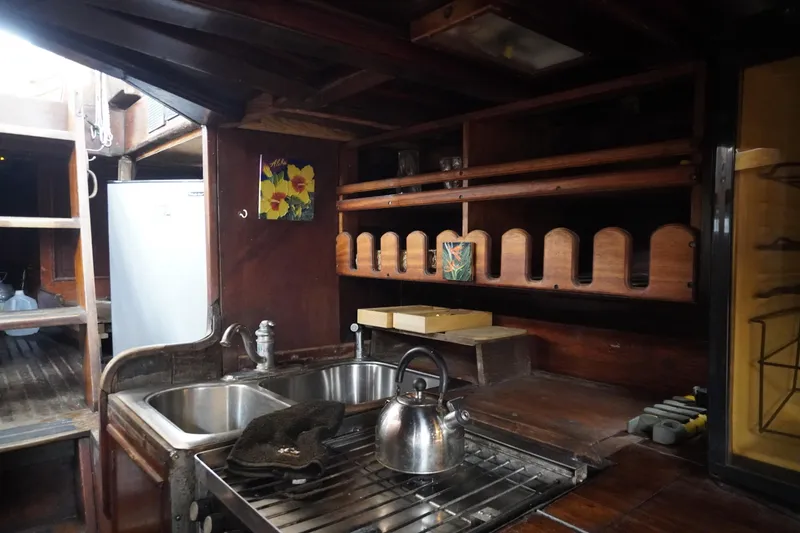 Slide: The Image of 1976 Manila Shipbuilders sailboat kitchen with wooden cabinets, sink, and stainless steel kettle. - 32
