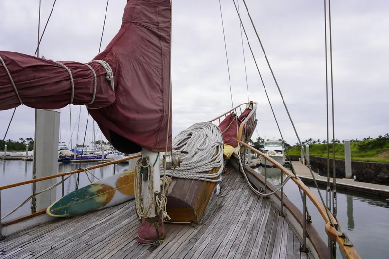 Slide: The Image of Vintage 1976 Manila Shipbuilders sailboat docked, featuring wooden deck and coiled ropes. - 5