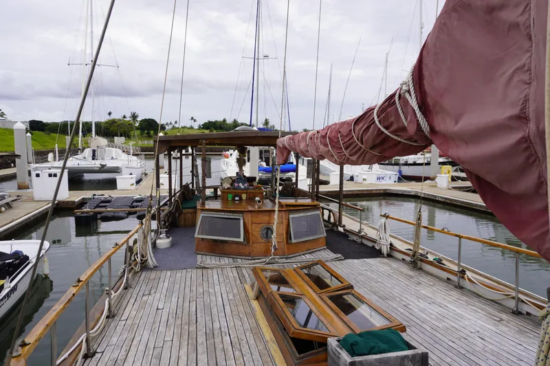 Slide: The Image of Vintage 1976 Manila Shipbuilders sailboat docked at marina, featuring wooden deck and red sail. - 53