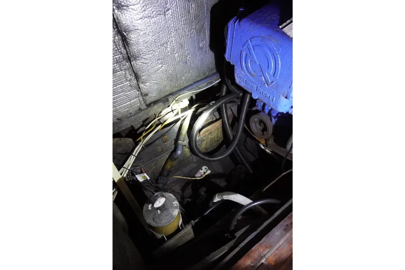 Slide: The Image of Engine compartment of a 1976 Manila Shipbuilders sailboat, featuring mechanical components and wiring. - 56