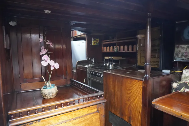 Slide: The Image of Interior of a 1976 Manila Shipbuilders sailboat with wooden cabinetry and floral decor. - 9