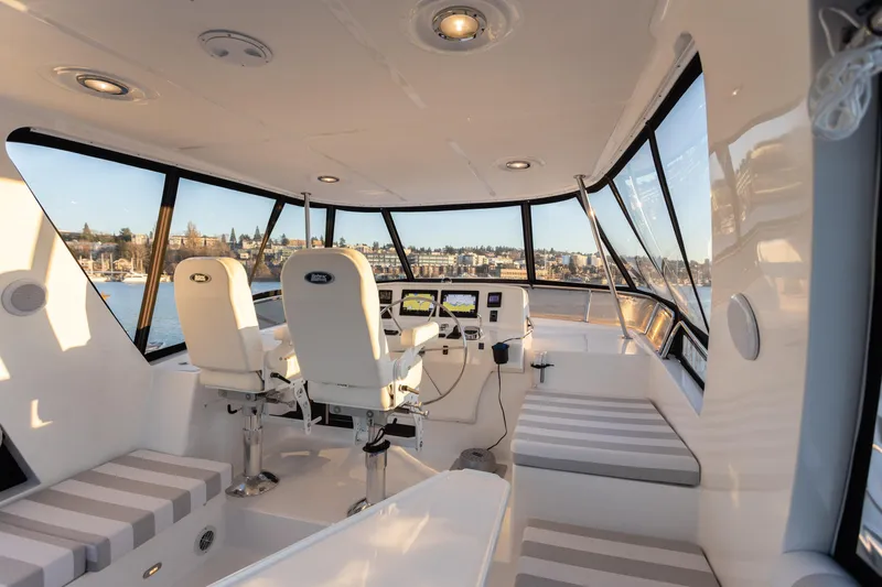 Slide: The Image of Pilothouse interior of 2021 North Pacific 49, featuring modern seating and panoramic windows. - 14