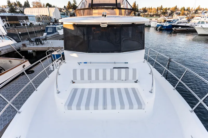Slide: The Image of 2021 North Pacific 49 Pilothouse yacht with striped seating, docked in a marina. - 22