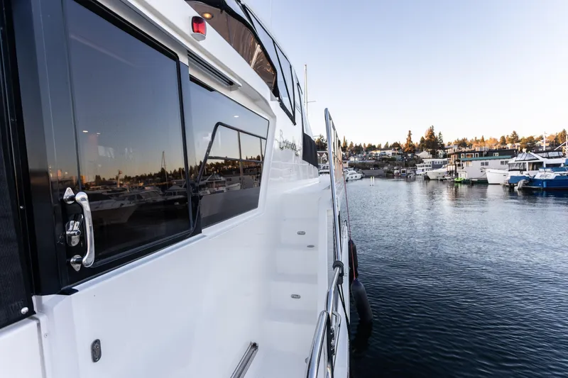 Slide: The Image of 2021 North Pacific 49 Pilothouse yacht docked in a serene marina setting. - 25