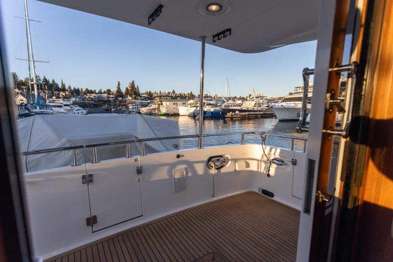 Slide: The Image of 2021 North Pacific 49 Pilothouse yacht deck overlooking marina with boats and clear sky. - 27
