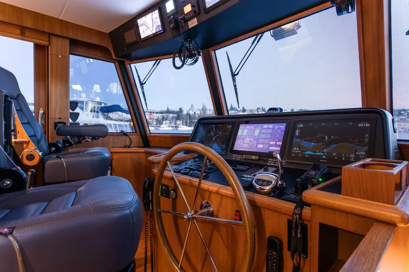 Slide: The Image of Pilothouse interior of 2021 North Pacific 49, featuring navigation screens and steering wheel. - 7