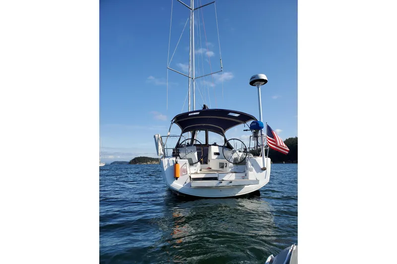 Slide: The Image of 2017 Jeanneau Sun Odyssey 349 sailboat on calm water, rear view with American flag. - 16