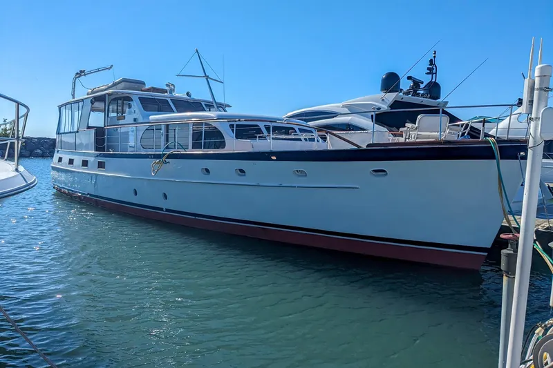 Slide: The Image of 1956 Burger Pilothouse yacht docked in a marina under clear blue skies. - 1