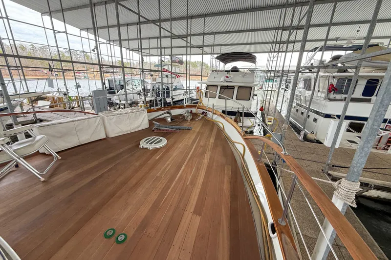 Slide: The Image of 1956 Burger Pilothouse yacht docked in marina, showcasing spacious wooden deck under covered shelter. - 16
