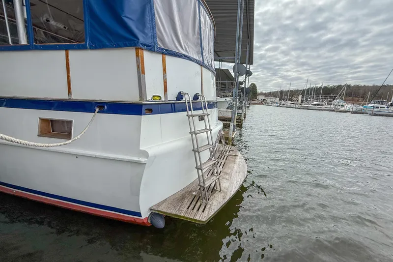 Slide: The Image of 1956 Burger Pilothouse boat docked at marina with ladder and calm water. - 3