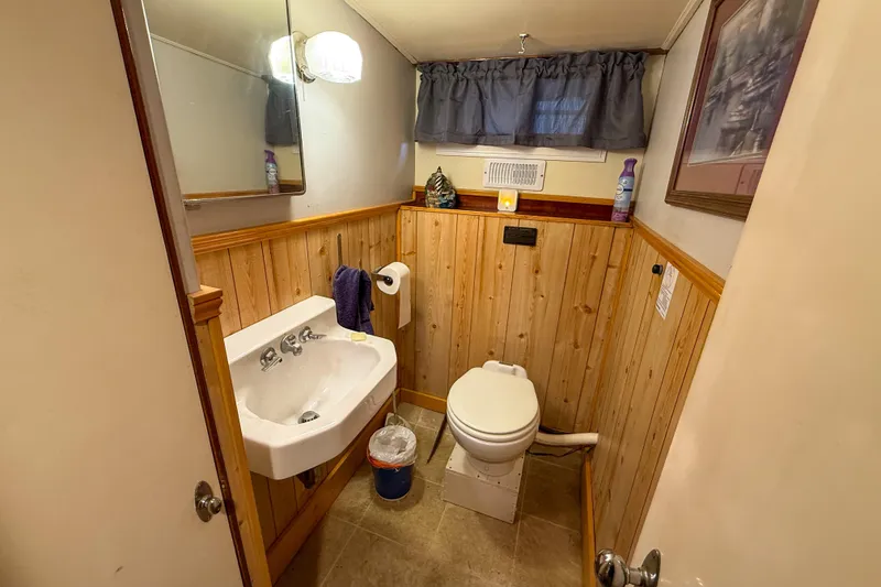 Slide: The Image of 1956 Burger Pilothouse bathroom with wood paneling, sink, and toilet. - 36