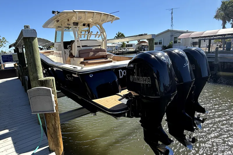 The Image of 2018 Scout 350 LXF boat with triple Yamaha engines docked at marina. - 0