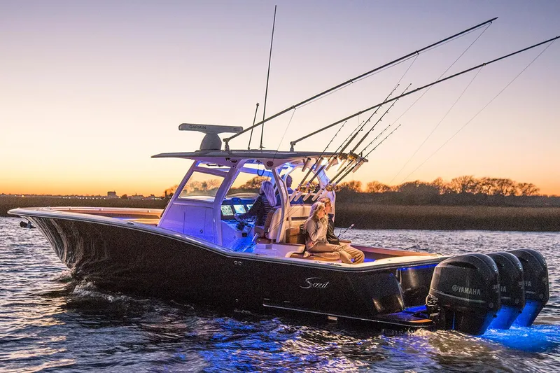Slide: The Image of Manufacturer Provided Image: 2018 Scout 350 LXF boat at sunset with fishing rods and Yamaha engines. - 2
