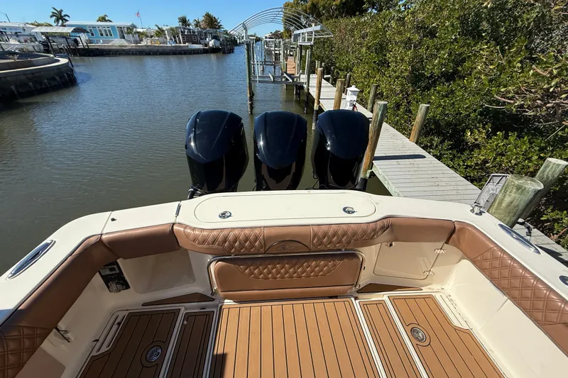 Slide: The Image of 2018 Scout 350 LXF boat with triple engines docked by a wooden pier. - 4