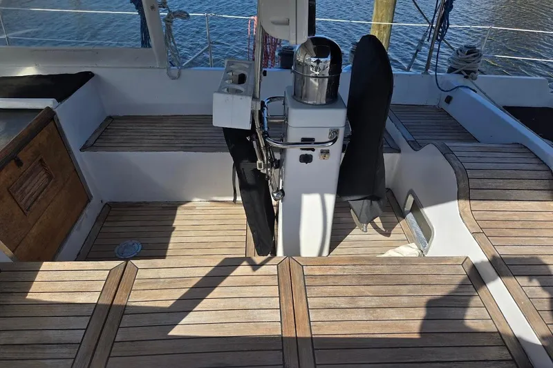 Slide: The Image of 1982 Tayana Center Cockpit Cutter Ketch with wooden deck and steering column, docked by water. - 17
