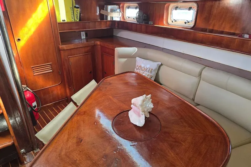 Slide: The Image of 1982 Tayana Center Cockpit Cutter Ketch interior with wooden table and beige seating. - 27
