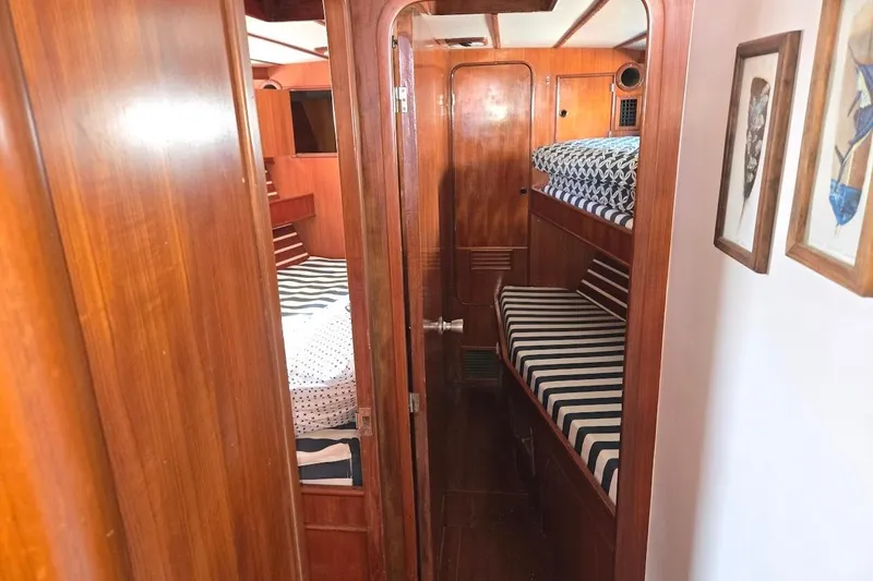 Slide: The Image of 1982 Tayana Center Cockpit Cutter Ketch interior with wooden finish and striped bedding. - 47