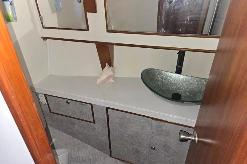 Slide: The Image of 1982 Tayana Center Cockpit Cutter Ketch bathroom with modern glass sink and wooden cabinetry. - 50