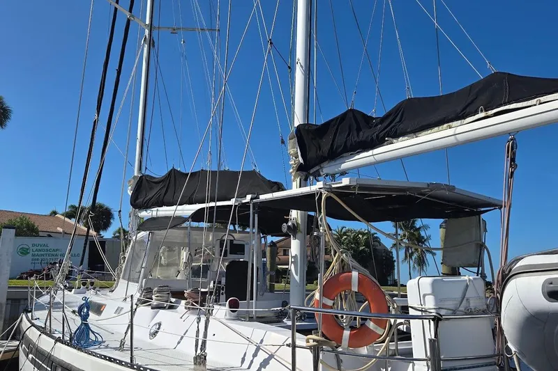 Slide: The Image of 1982 Tayana Center Cockpit Cutter Ketch docked, featuring sails and lifebuoy under clear blue sky. - 56