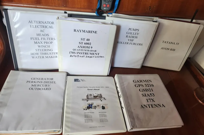 Slide: The Image of Binders with manuals for Tayana Center Cockpit Cutter Ketch, 1982, featuring various equipment and systems. - 71