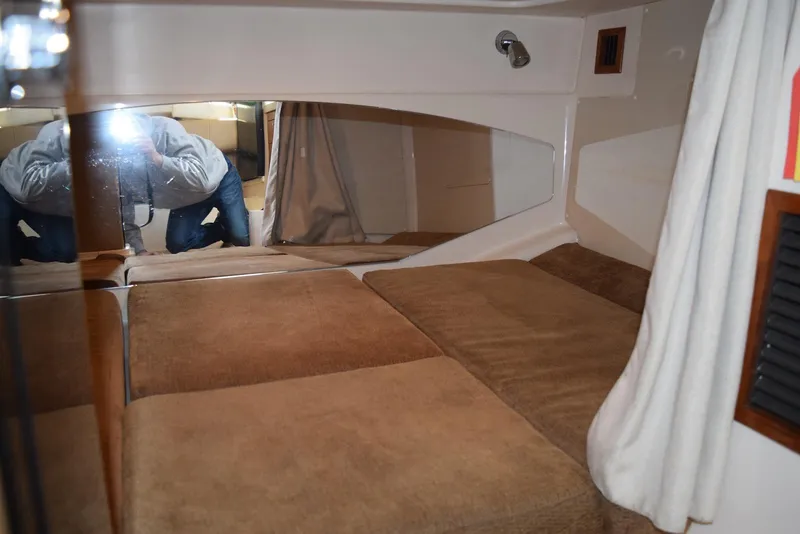 Slide: The Image of 2013 Grady-White Express 330 cabin interior with brown cushions and mirrored wall. - 27