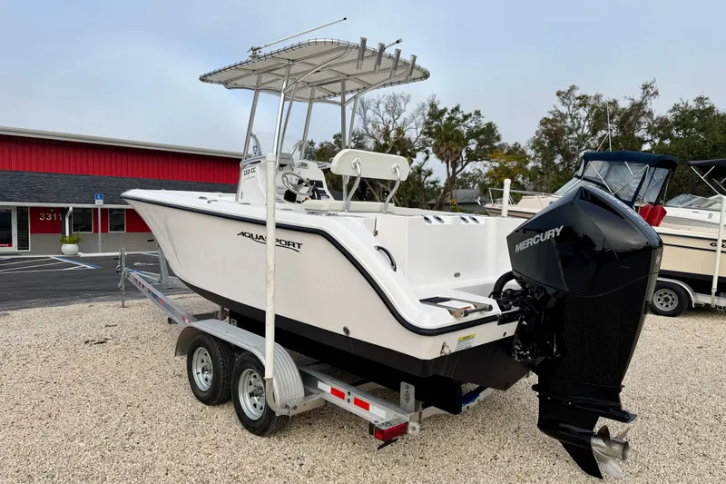 Slide: The Image of 2023 Aquasport 220 CC boat on trailer with Mercury outboard engine, parked outdoors. - 5