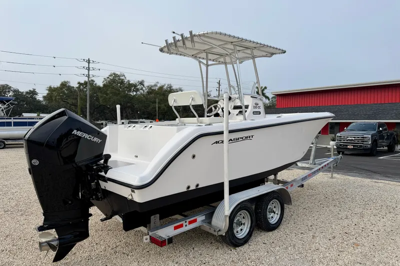 Slide: The Image of 2023 Aquasport 220 CC boat on trailer with Mercury outboard engine, parked outdoors. - 7