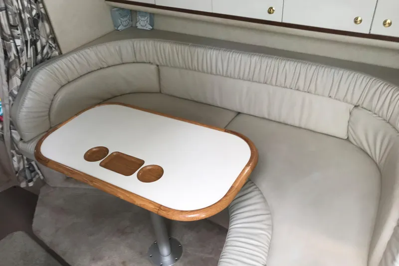 Slide: The Image of 1997 Sea Ray Sundancer 330 interior with cushioned seating and wooden table. - 10