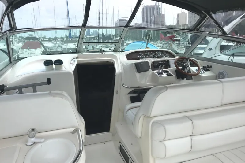 Slide: The Image of 1997 Sea Ray Sundancer 330 cockpit with white seating and helm, docked in marina. - 7