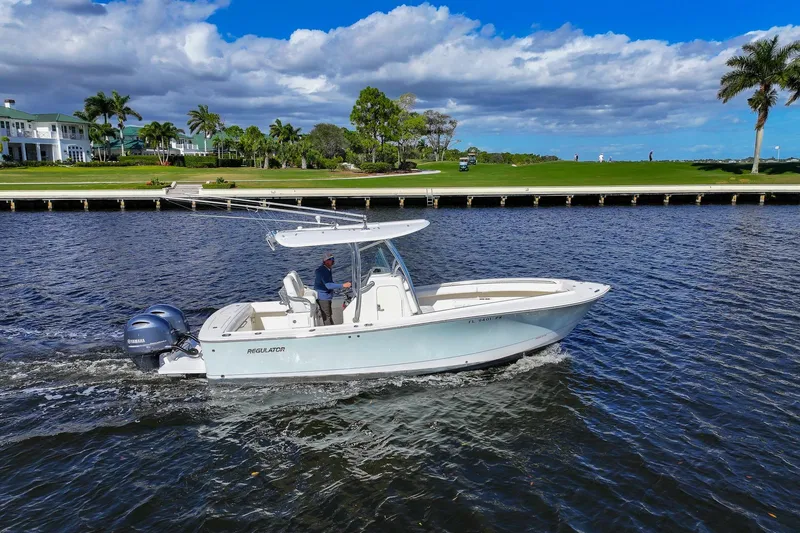 The Image of 2014 Regulator 25 boat cruising on a scenic lake with lush shoreline. - 0