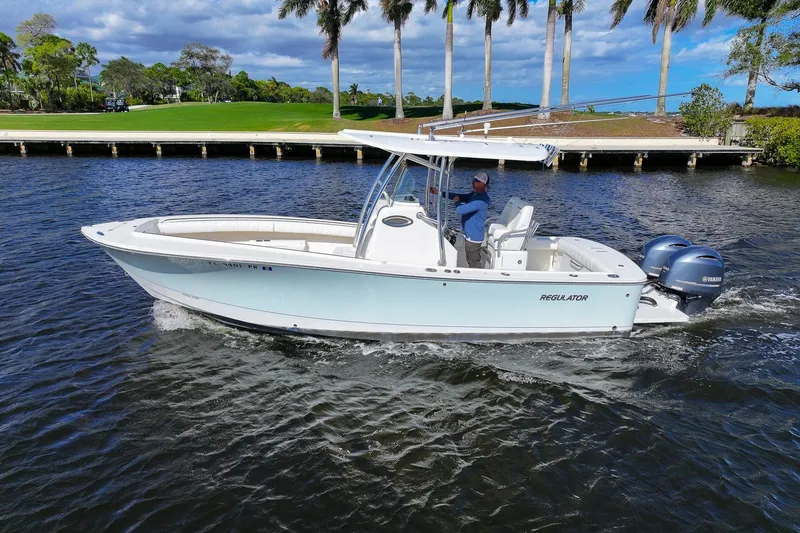 Slide: The Image of 2014 Regulator 25 boat cruising on open water, rear view with twin engines. - 14