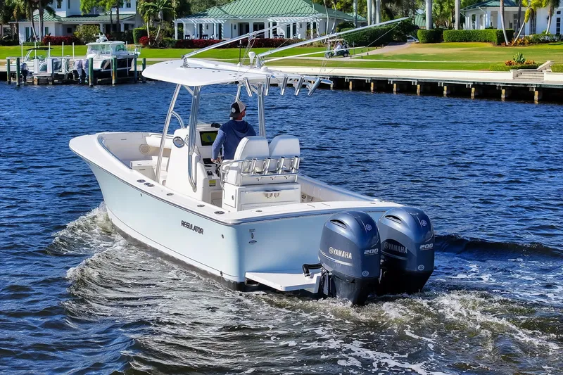 Slide: The Image of 2014 Regulator 25 boat cruising on open water with twin engines. - 15