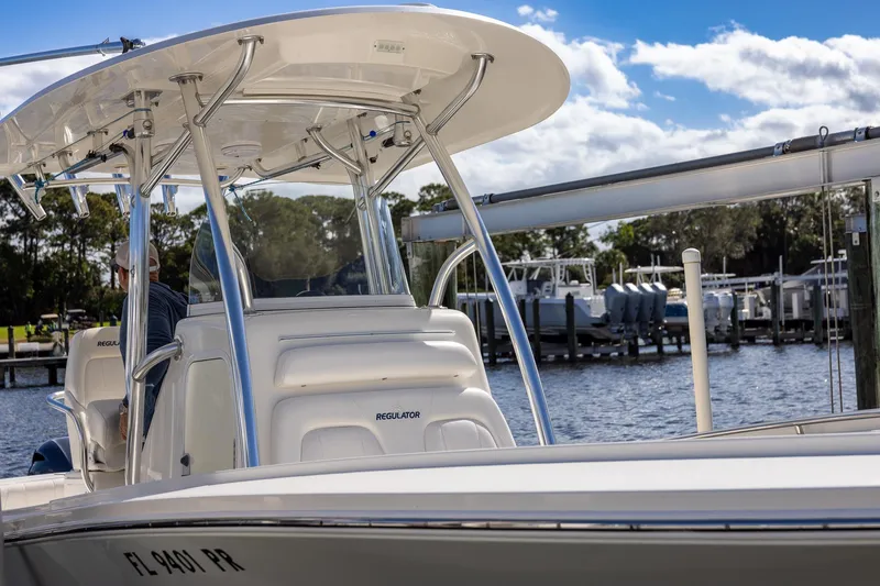Slide: The Image of 2014 Regulator 25 boat seats with white upholstery, docked by the water. - 31