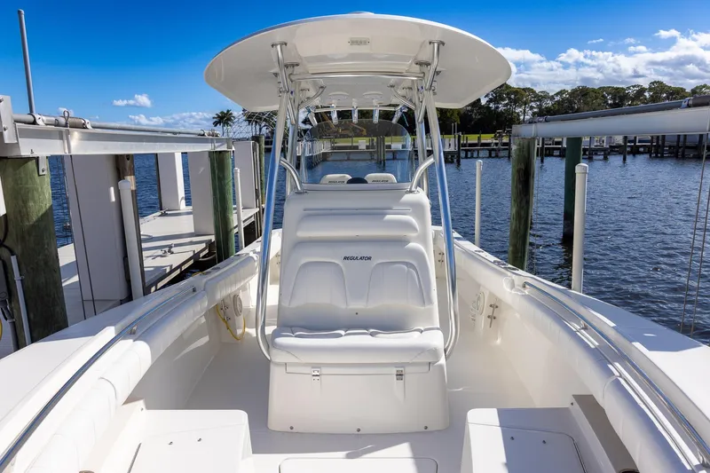 Slide: The Image of 2014 Regulator 25 boat docked, featuring sleek white seating and a sunny waterfront view. - 39
