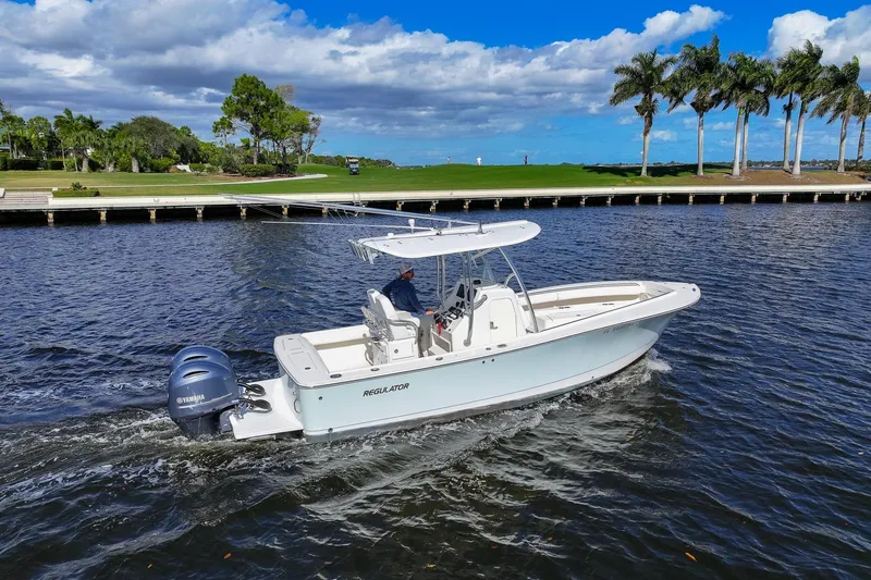Slide: The Image of 2014 Regulator 25 boat cruising on a scenic waterway with palm trees in the background. - 5